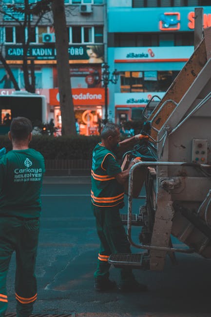 A person wearing a bright yellow raincoat, matching trousers, and a face mask with the words 'END SARS' printed on an orange cap, is seen cleaning underneath a concrete bridge or overpass. They are us